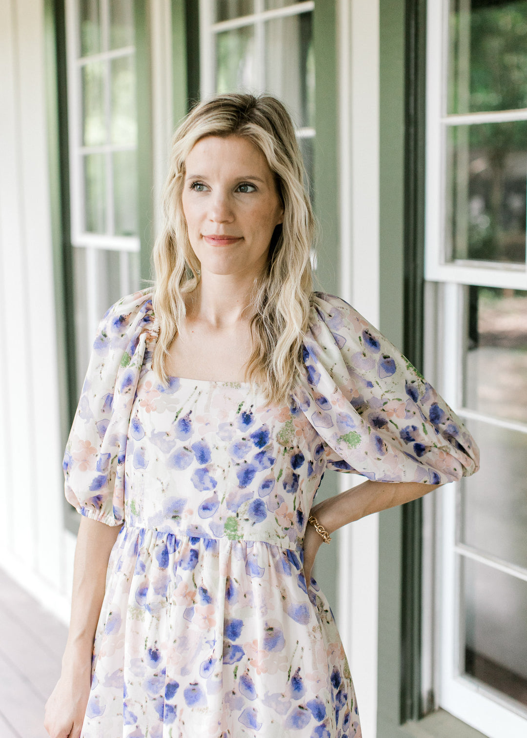 Model wearing a cream dress with watercolor floral, square neck and bubble short sleeves.