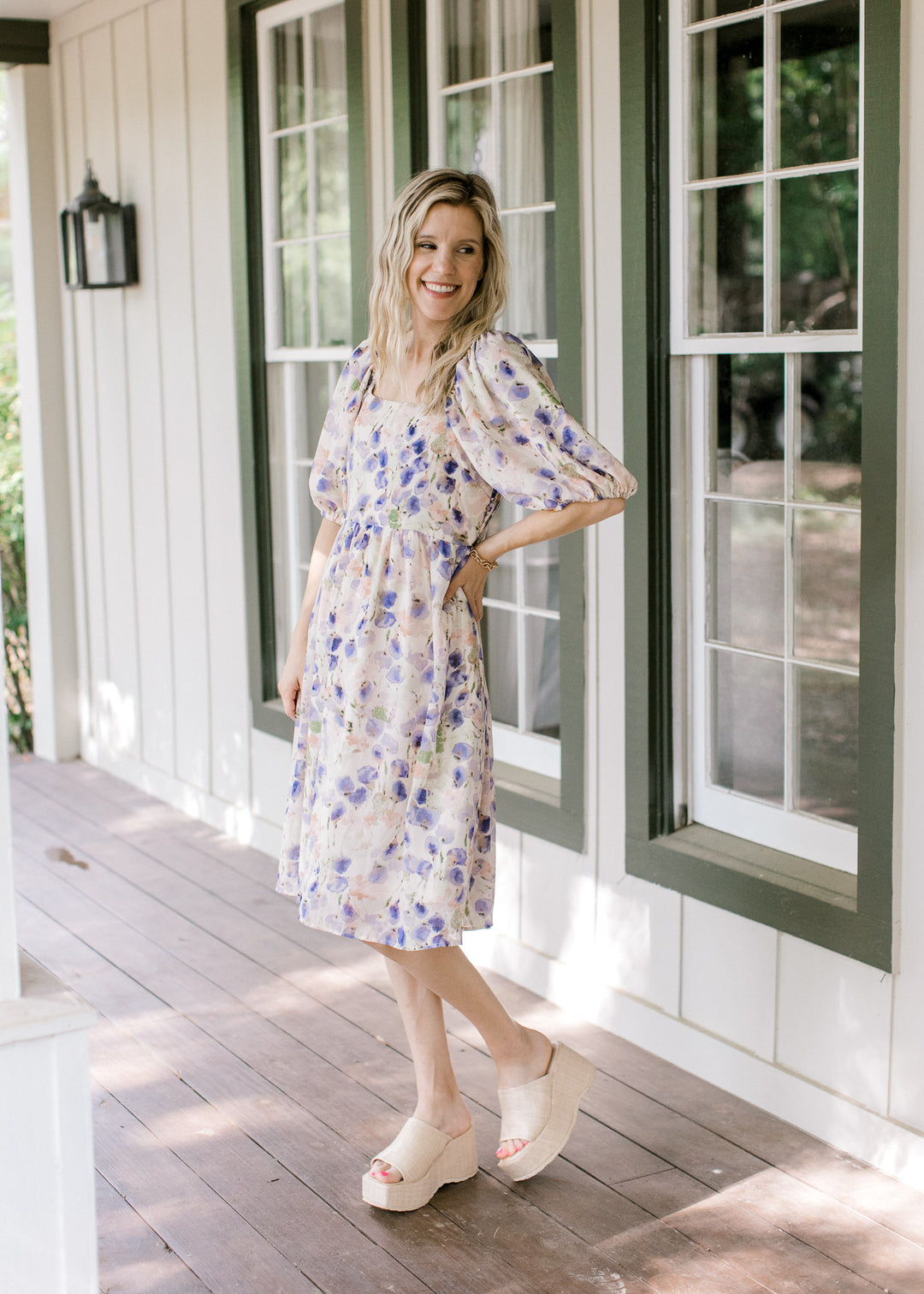 Model wearing wedges with a cream dress with violet, green and pink watercolor floral. 