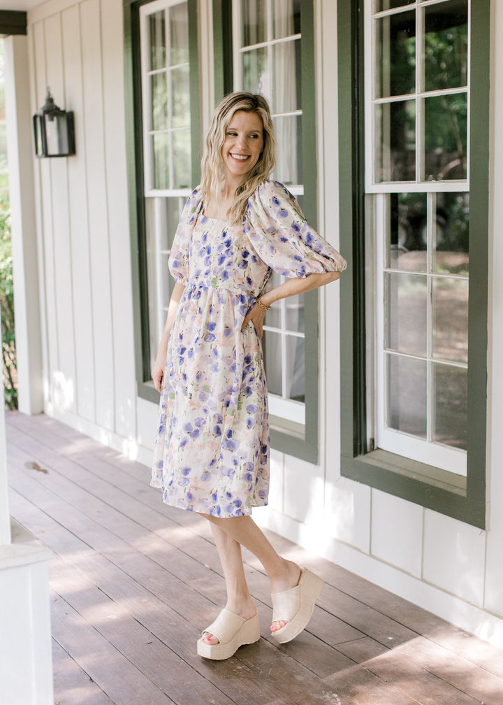Model wearing wedges with a cream dress with violet, green and pink watercolor floral. 