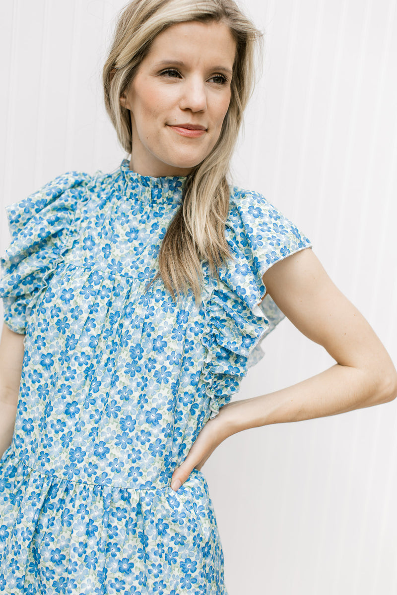 Close up of mock neck and ruffle cap sleeves on a mint dress with blue floral.