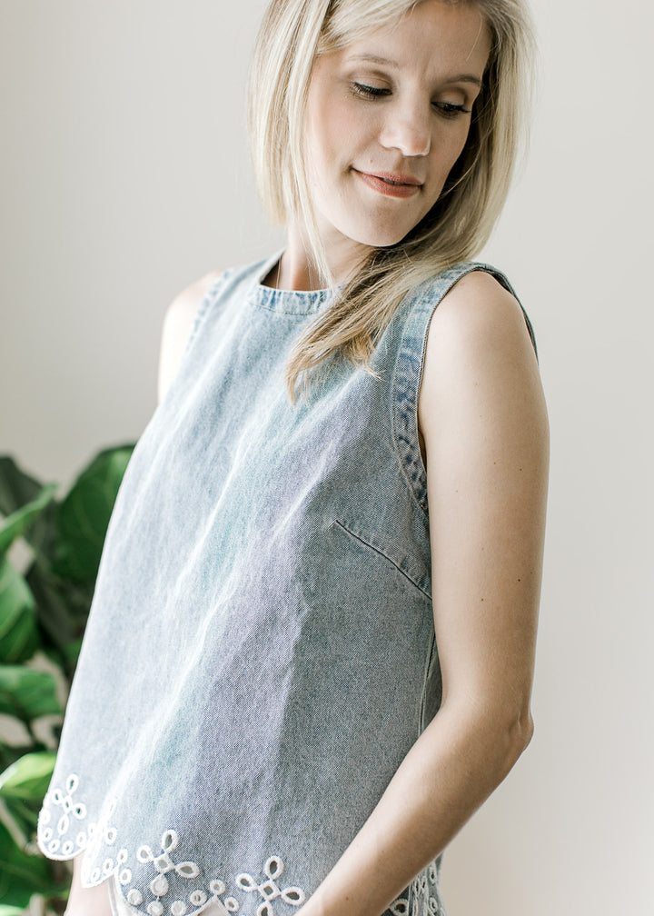 Side view of Model wearing a light wash top with scalloped hem and embroidered eyelet at hem.