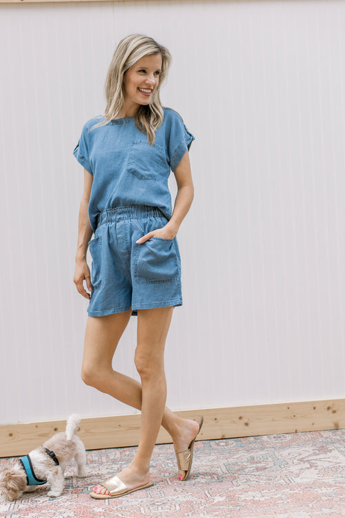 Model wearing a chambray set with elastic waist in shorts and patch pocket on top.