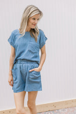 Model wearing a chambray set with elastic waist in shorts and a short sleeve top.