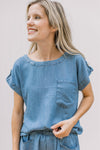 Model wearing chambray shorts and top with patch pockets and a round neck.