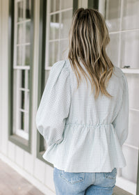 Back view of Model wearing a babydoll blue and white checkered top with 3/4 bubble sleeves. 