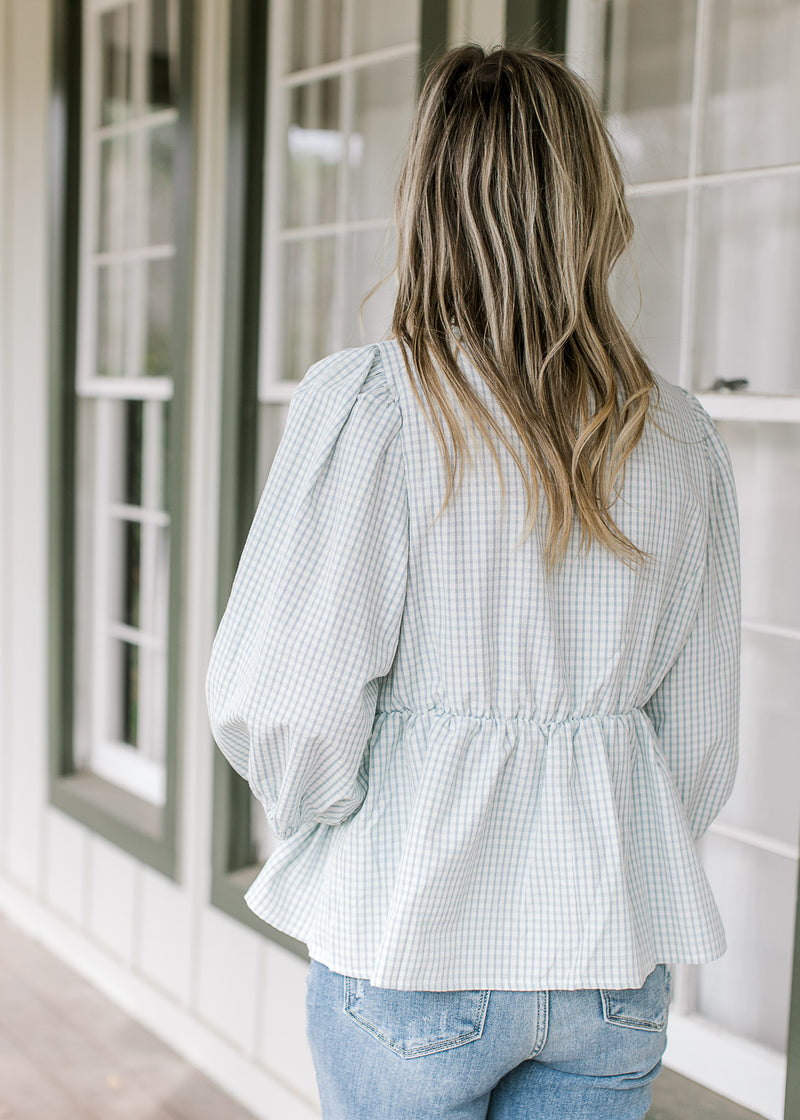 Back view of Model wearing a babydoll blue and white checkered top with 3/4 bubble sleeves. 