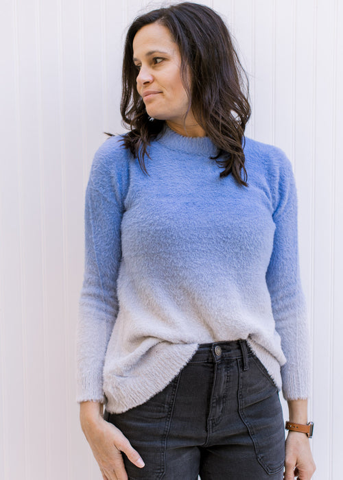 Model wearing a two toned blue sweater with long sleeves, a nylon material and a round neck. 