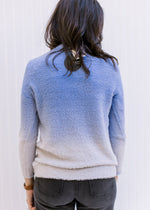 Back view of  Model wearing a two toned blue sweater with long sleeves and a round neck.