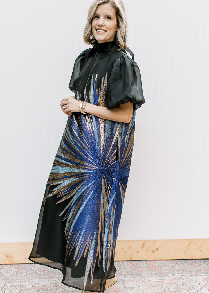Angled view of Blue Flame Dress showing metallic blue and gold starburst, mock neckline and sheer bubble sleeves.