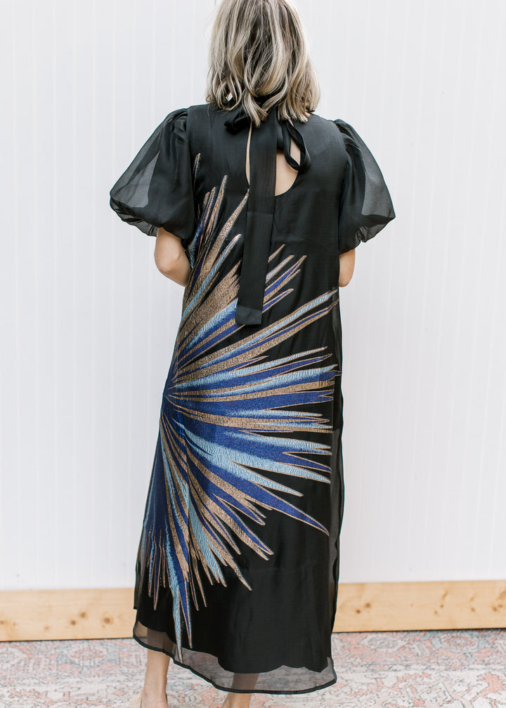 Back view of Blue Flame Dress with long neckline ties, keyhole opening and metallic blue and gold starburst.