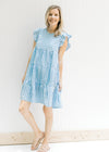 Model wearing sandals with a blue and white tiered gingham dress with ruffle cuff sleeves. 