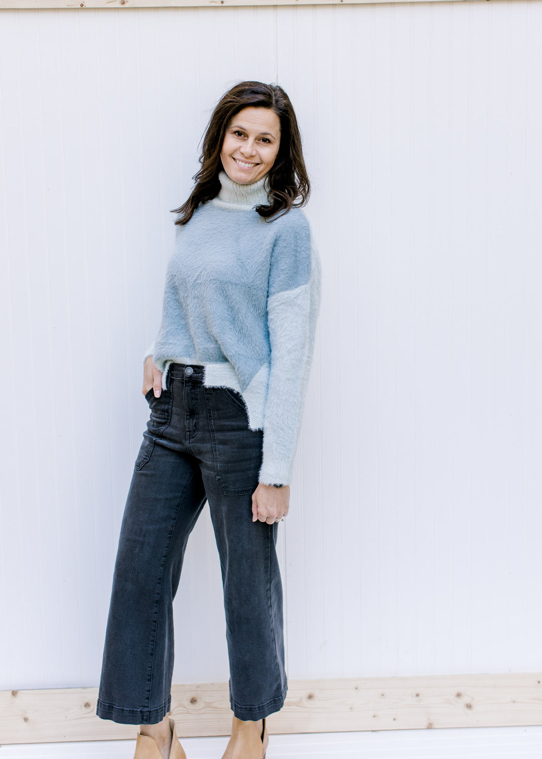 Model wearing jeans and a blue and gray colorblock sweater with long sleeves and split sides.