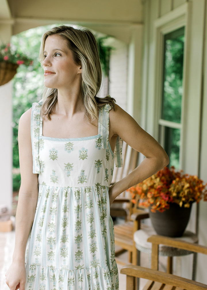 Model wearing a cream midi with blue and green floral, elastic smocked back and tiered skirt.