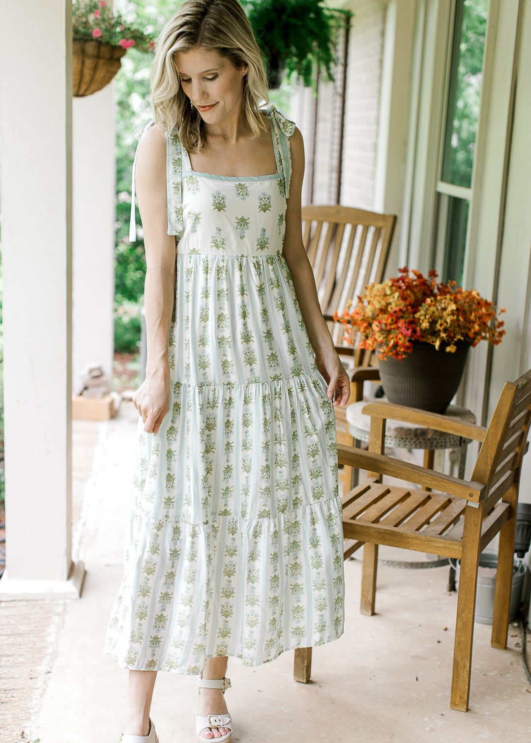 Model wearing heels and a cream midi with blue and green floral, smocked back and tiered skirt.