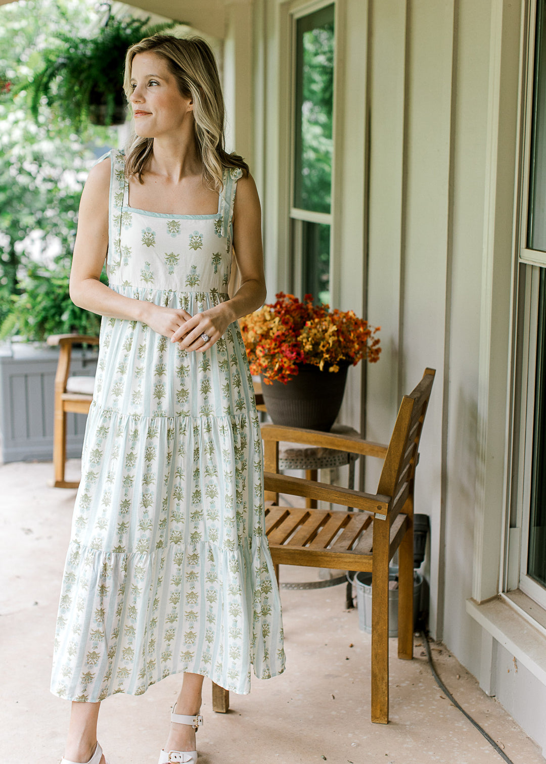 Model wearing a cream tiered midi with blue and green striped floral and elastic smocked back. 