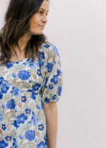 Close up of bubble short sleeve on a babydoll cream dress with blue, green and orange floral.