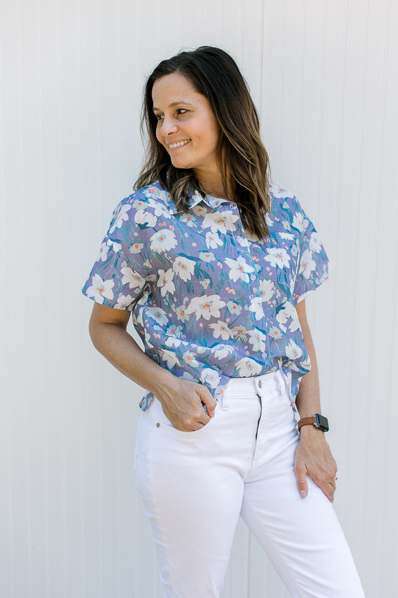 Model wearing a lavender top with flowers, short sleeves and buttons front.