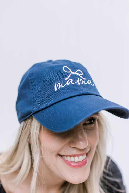 Model wearing an blue adjustable size hat with embroidered script mama with a pink bow.