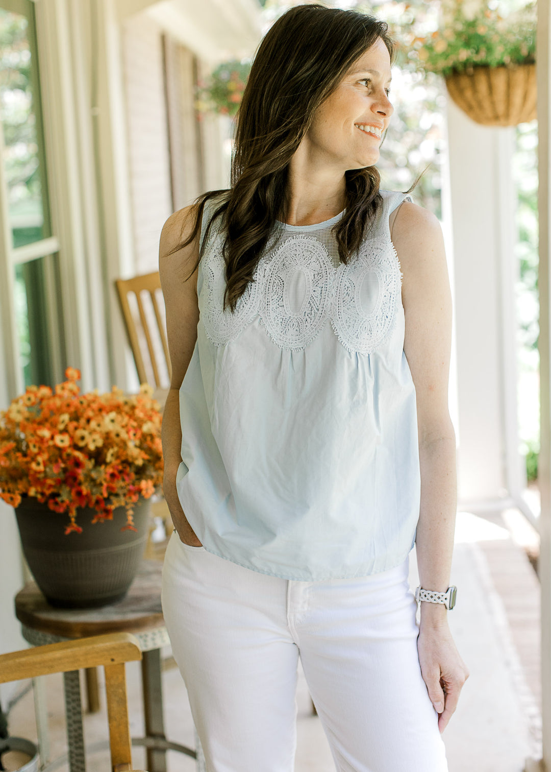 Model wearing white pants and a baby blue top with mesh yoke, stitched medallions on front.
