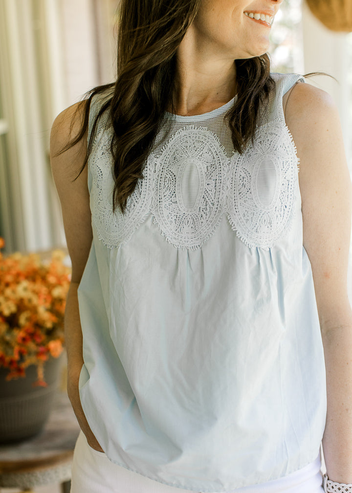 Close up of three stitched medallions on the front of a sleeveless baby blue top with mesh yolk.