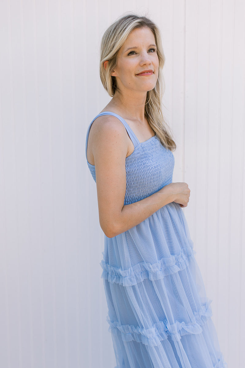 Model wearing a pale blue maxi with tank straps, smocked bodice and tiered mesh skirt.