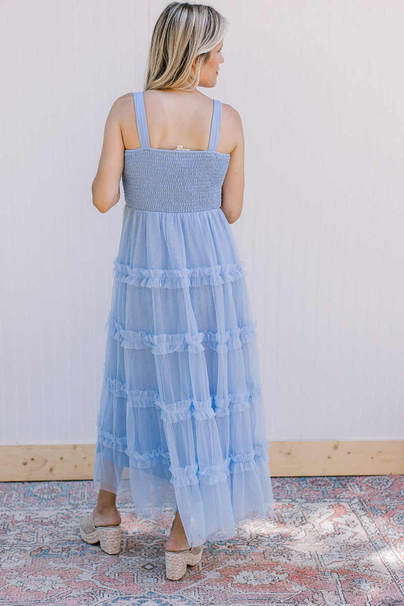 Back view of Model wearing a pale blue maxi with tank straps, smocked bodice and mesh skirt.