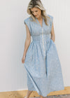 Model wearing a sleeveless blue and white checked midi with a front zipper and a smocked waist. 