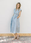 Model wearing heels and a blue and white checked midi with a front zipper and a smocked waist. 