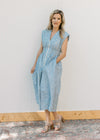 Model wearing a sleeveless blue and white checked midi with pockets and a smocked waist. 