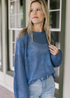 Model wearing a blue open weave knit sweater with stitched flowers and bubble long sleeves.