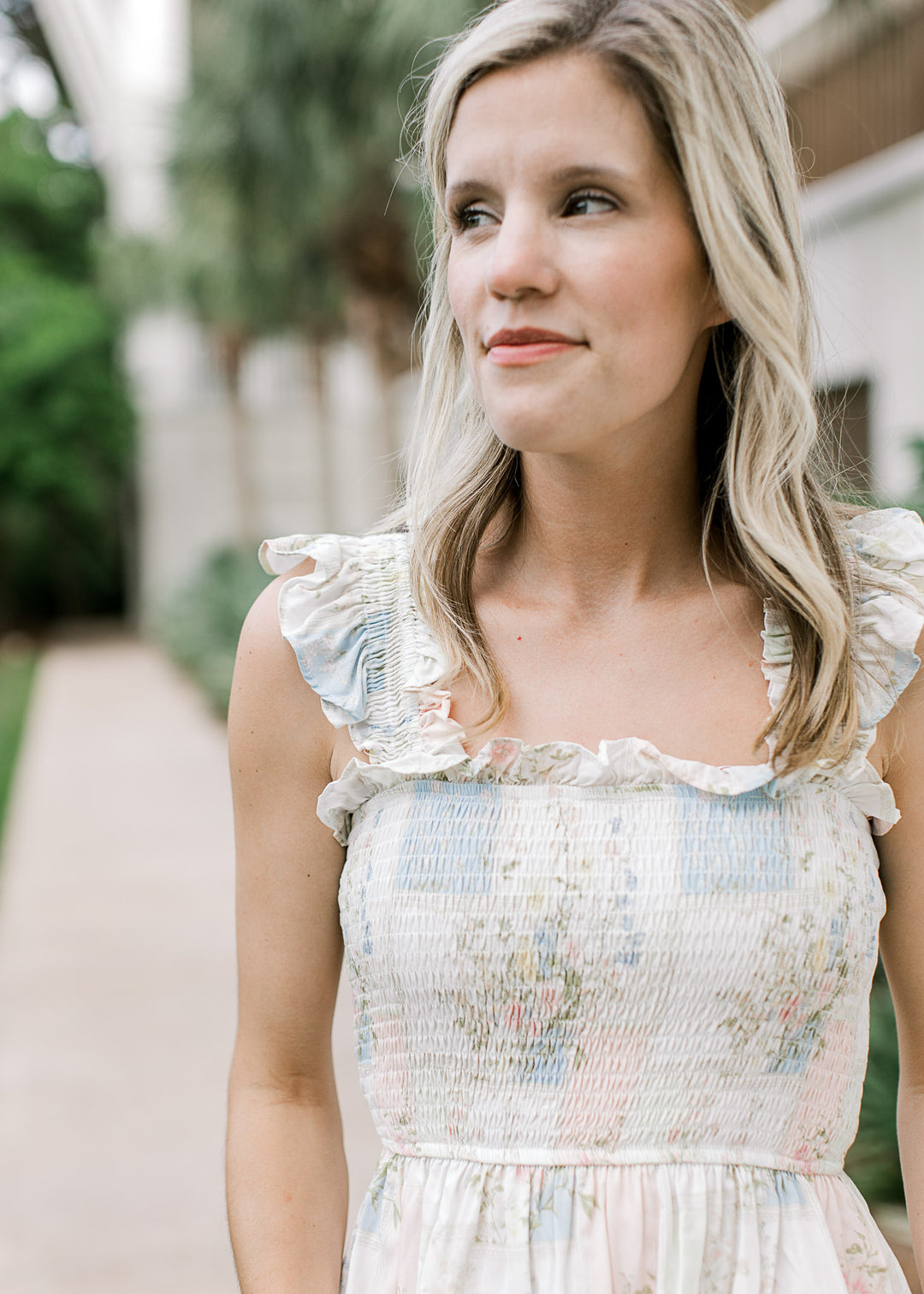 Model wearing a smocked white top with pink and pale blue pattern with a square neck. 
