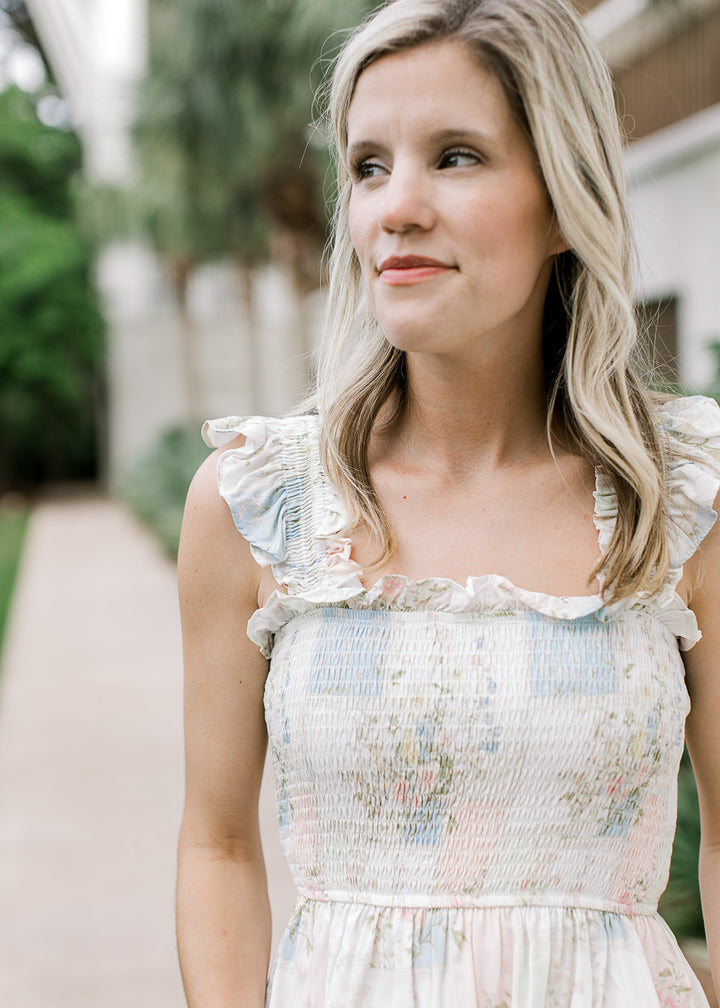 Model wearing a smocked white top with pink and pale blue pattern with a square neck. 
