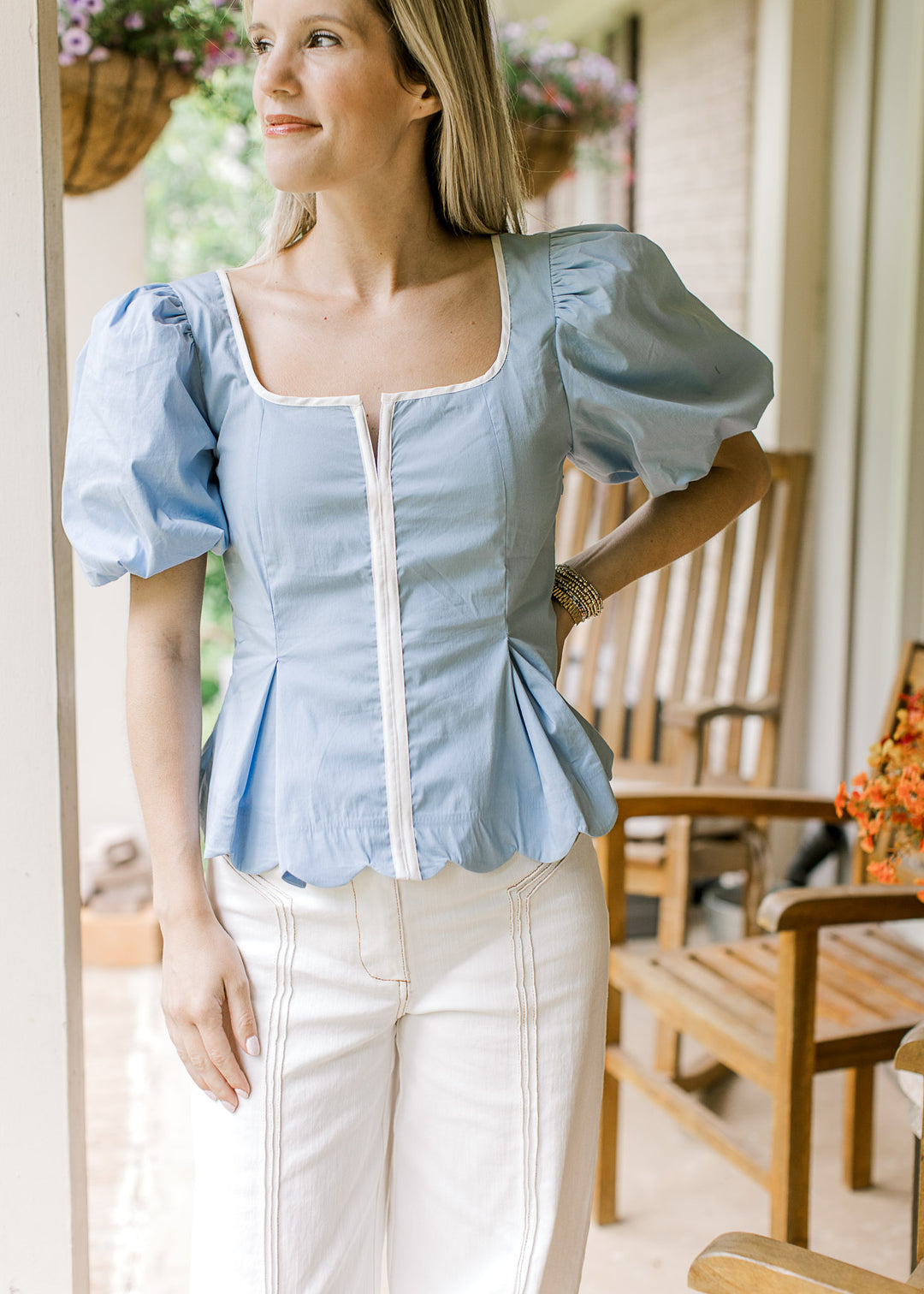 Model wearing a baby blue top with white piping at placket and scoop neck and bubble short sleeves.