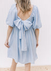 Back view of a pale blue dress with a tie back, bubble short sleeves and a square neck. 