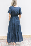 Back view of Model wearing a blue maxi with smocked wasitband and short puff sleeves.