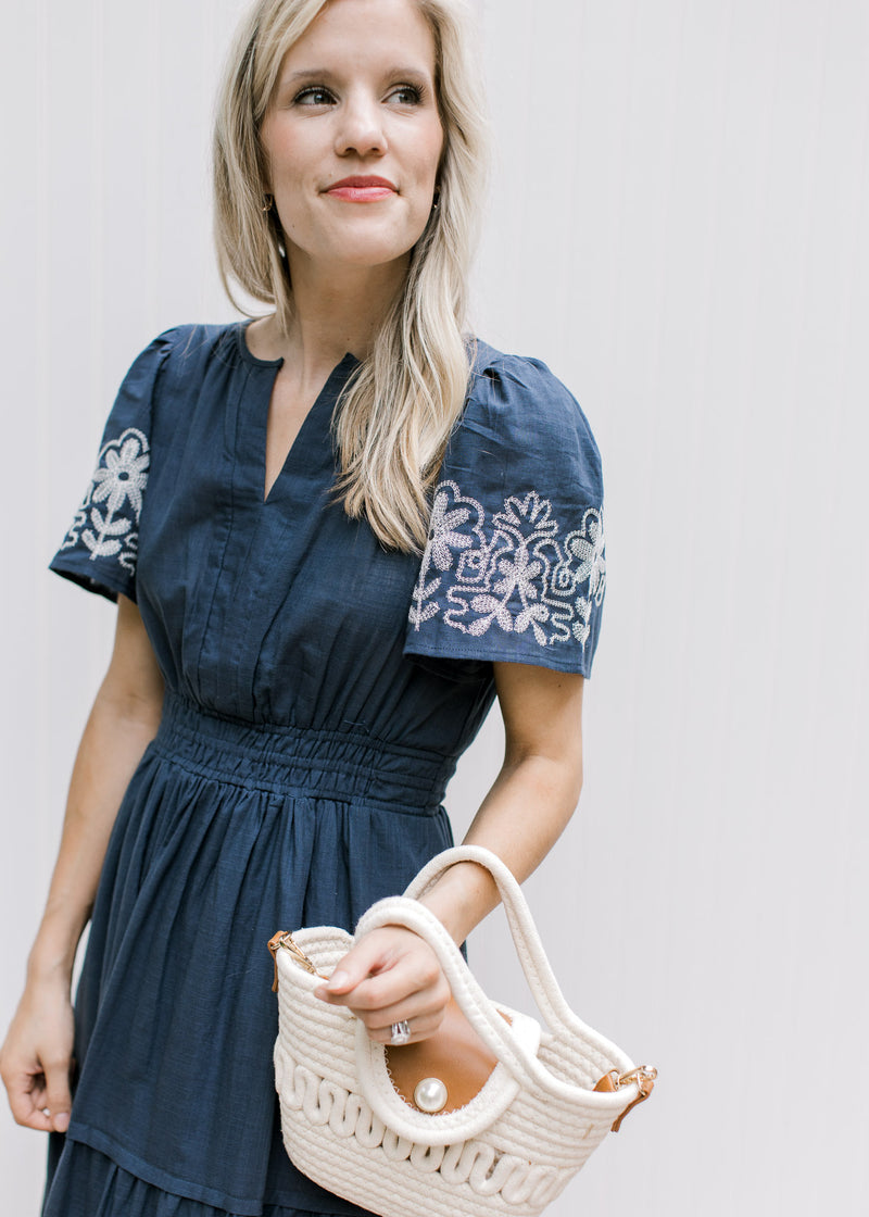 Close up view of v-neck and smocked waist on a blue maxi with white flowers and short sleeves.