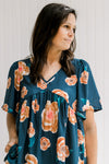Model wearing a navy babydoll top with an orange floral patter, v-neck and short sleeves.