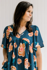 Model wearing a navy babydoll top with an orange floral patter, v-neck and short sleeves.