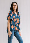 Model wearing jeans with a navy babydoll top with an orange floral patter, v-neck and short sleeves.