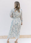 Back view of Model wearing a cream midi with blue roses, an elastic waist and sheer 3/4 sleeves.