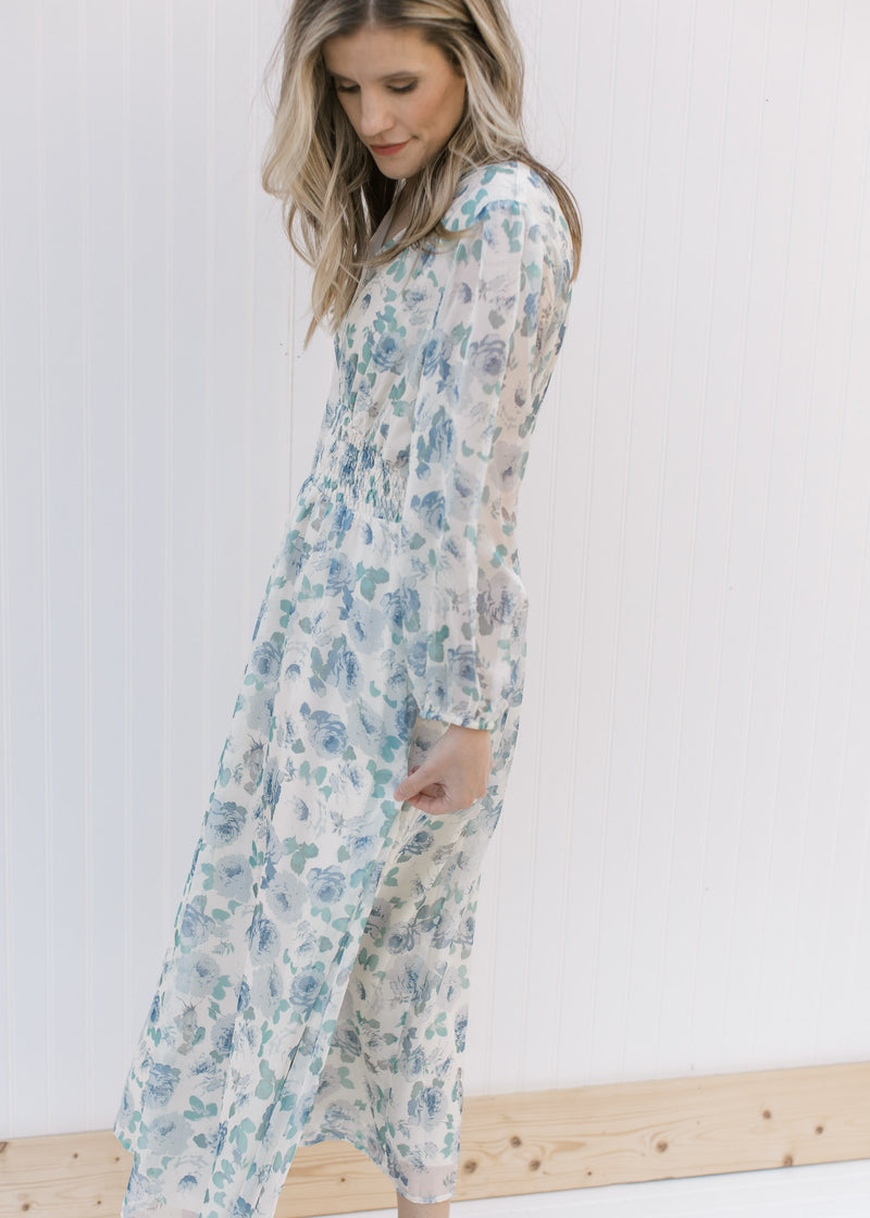 Side view of Model wearing a cream midi with blue roses, an elastic waist and sheer 3/4 sleeves.