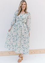 Model wearing heels with a cream midi with blue roses, an elastic waist and sheer 3/4 sleeves.
