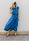 Model wearing a blue skirt set, with a cropped balloon top and pleated hi-low midi skirt. 