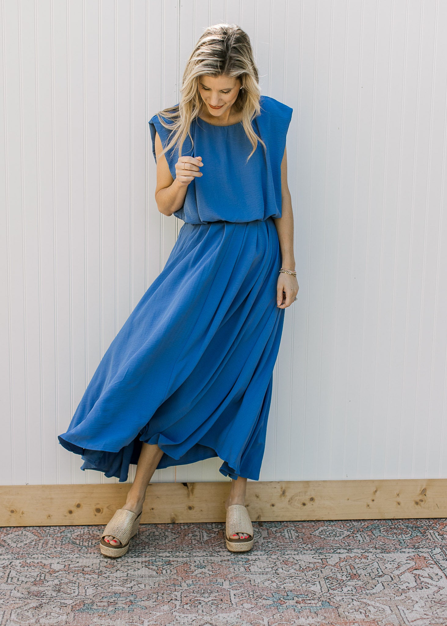 Model wearing a blue skirt set, with a cropped balloon top and pleated hi-low midi skirt. 