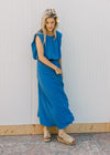 Model wearing wedges and a blue skirt set, with a cropped balloon top and pleated midi skirt. 