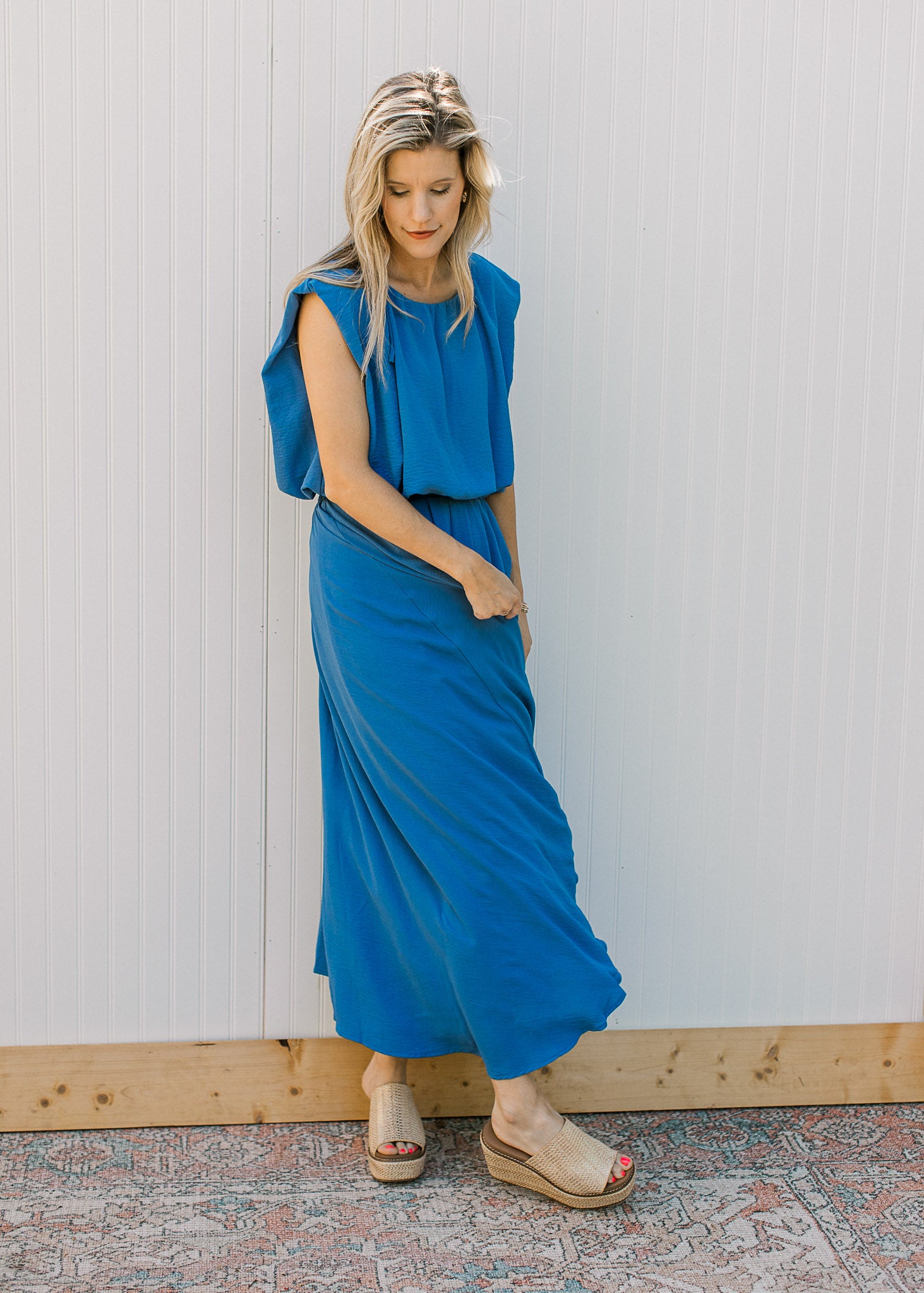 Model wearing wedges and a blue skirt set, with a cropped balloon top and pleated midi skirt. 