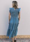 Back view of Model wearing a dusty blue midi with a smocked bodice and flutter cap sleeves. 