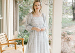 Model wearing a cream dress with blue floral, square neckline, smocked back and 3/4 bubble sleeves. 