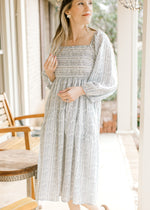 Model wearing a cream midi with blue floral, square neckline, smocked back and 3/4 bubble sleeves. 