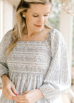 Close up of square neck and bubble sleeves on a cream midi with navy flowers and pale blue stripes.